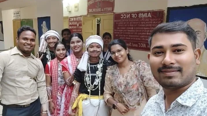 Participants in cultural costumes smiling for a group selfie.